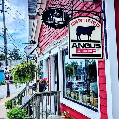 Exterior of a restaurant with signage for Fireworks Texas BBQ, Certified Angus Beef, and a satellite dish on the wall.