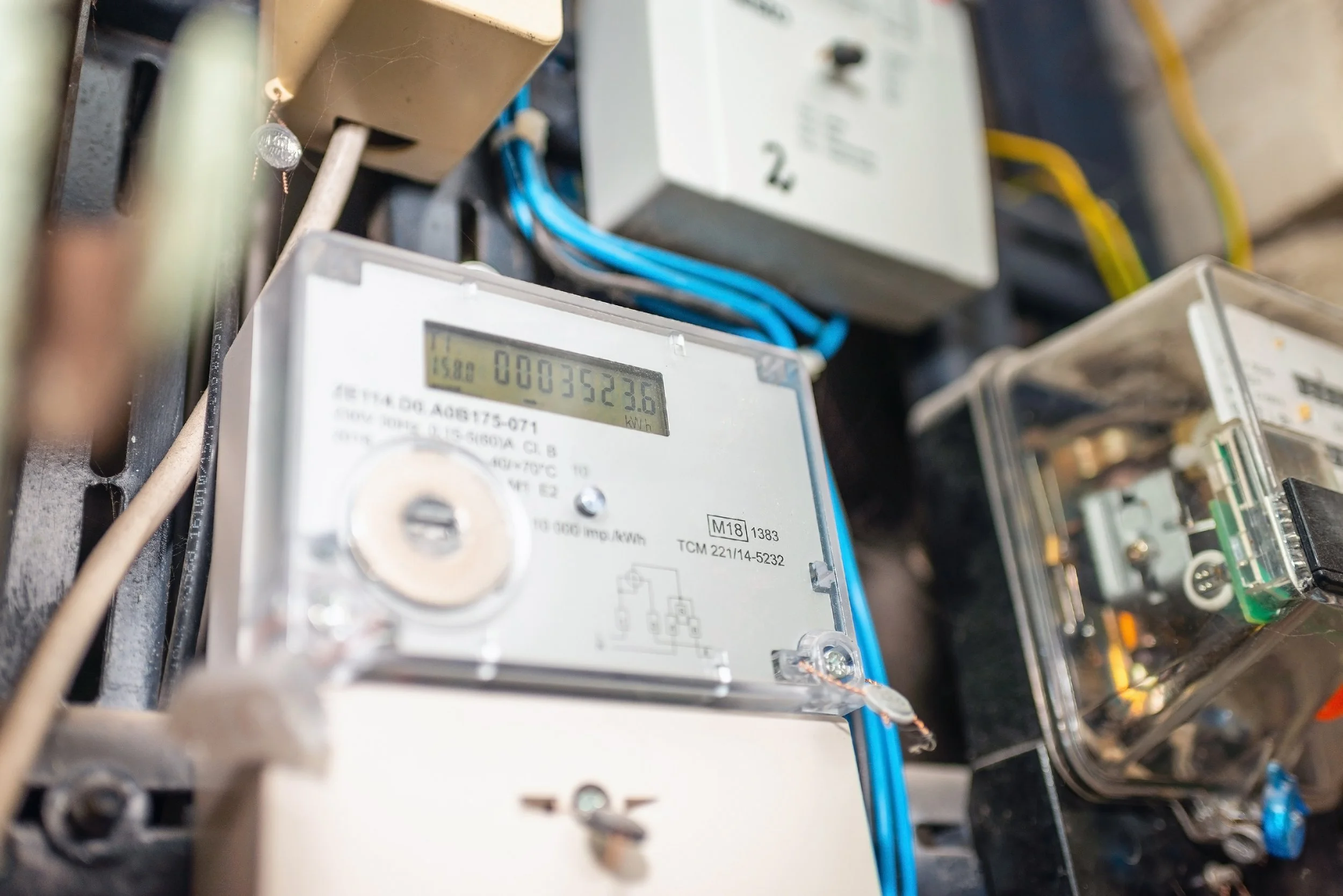 Close-up of an electric meter showing a digital reading and cables.