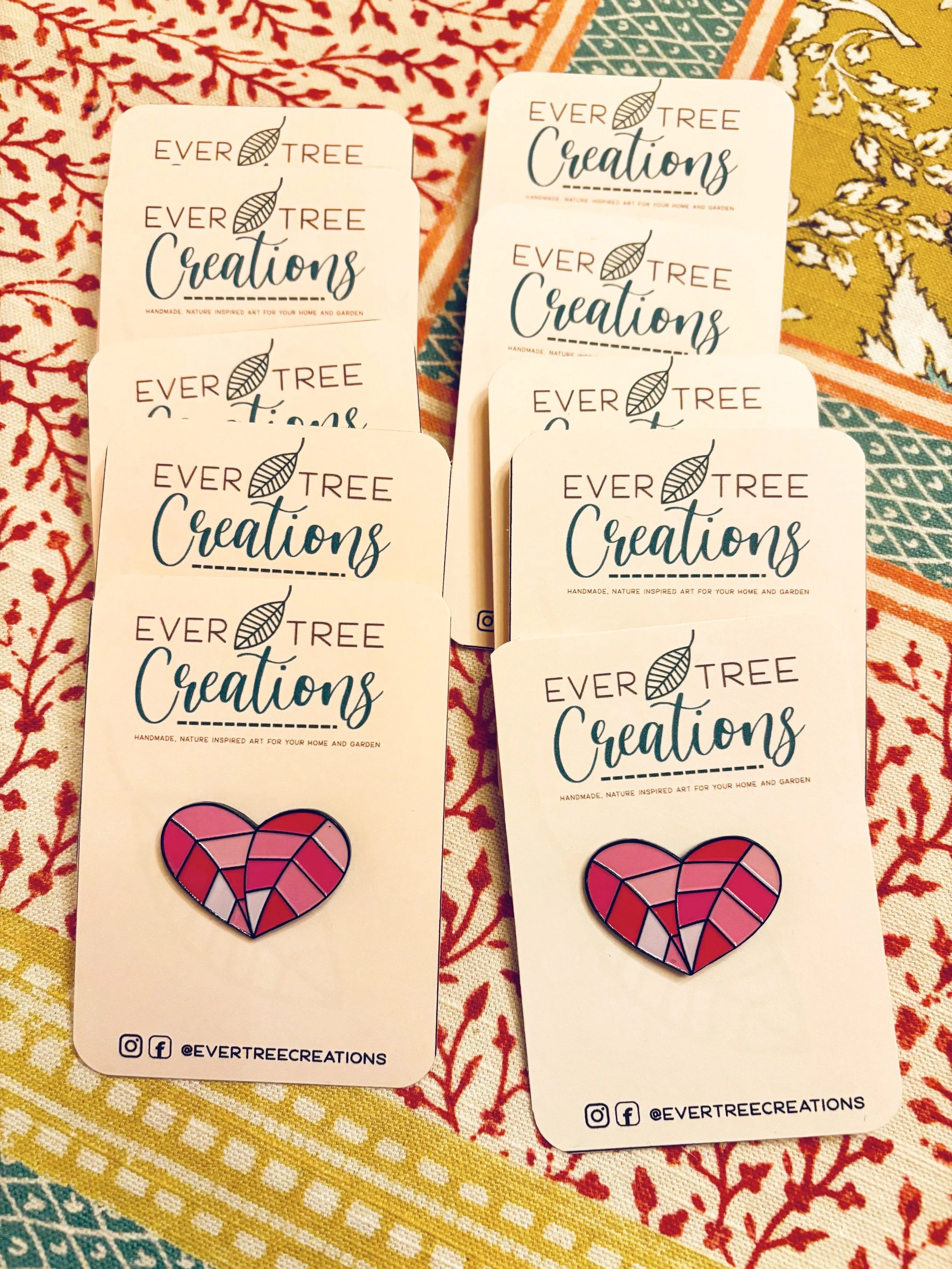 Set of promotional tags from Ever Tree Creations, each featuring a pink and red mosaic-style heart pin, placed on colorful patterned fabric.