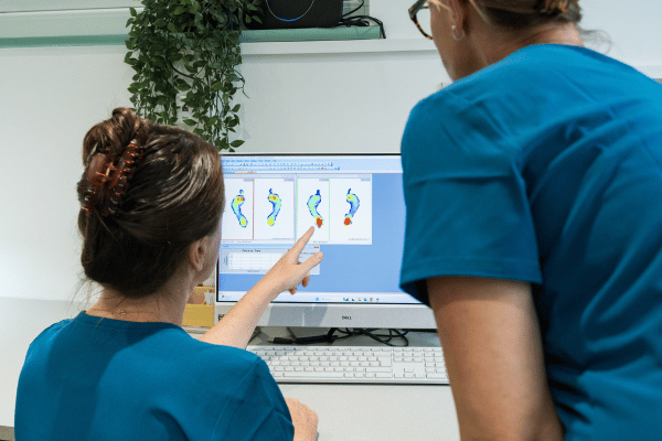 Image is of two podiatrists reviewing an orthotics foot scan at The Beale Clinic near Haywards Heath