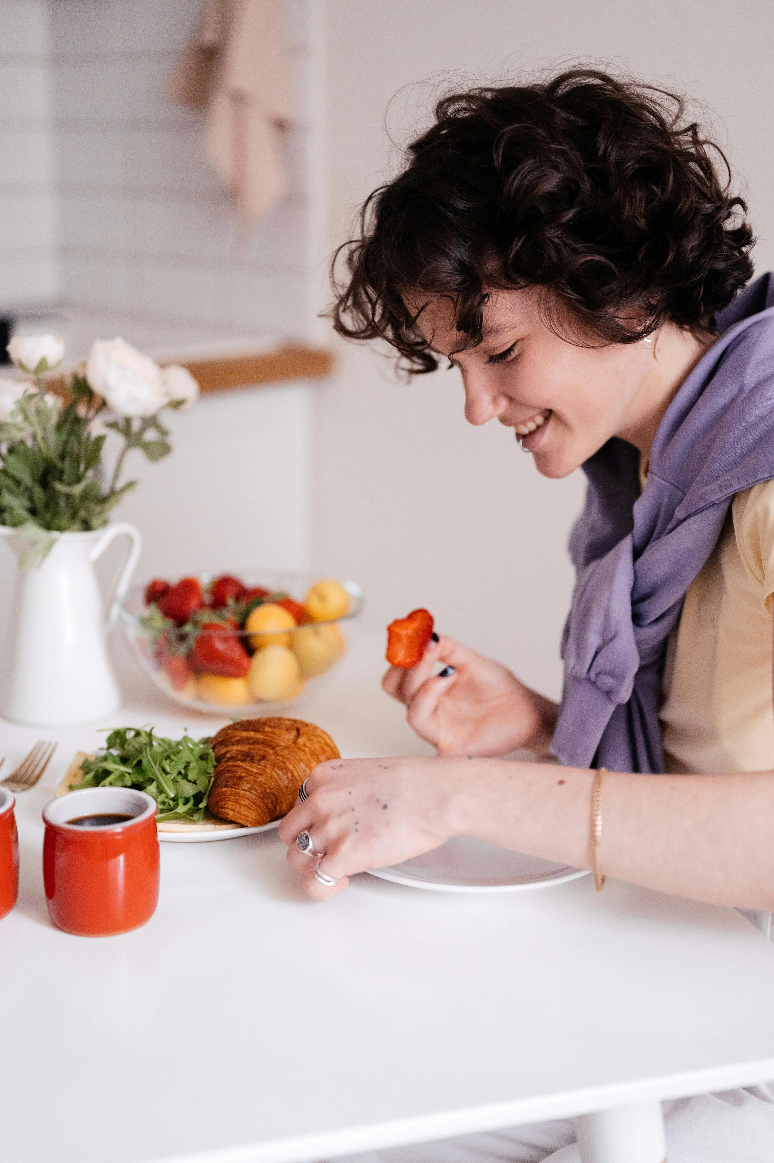 a woman eating a balanced meal of a pastry, fruit, and salad