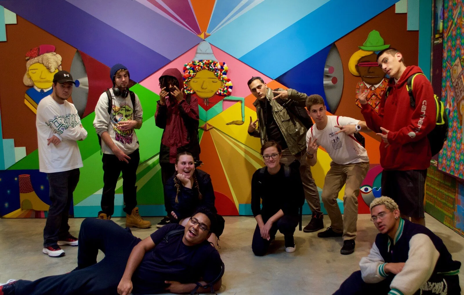 Group of City-As-School students posing in front of colorful wall mural