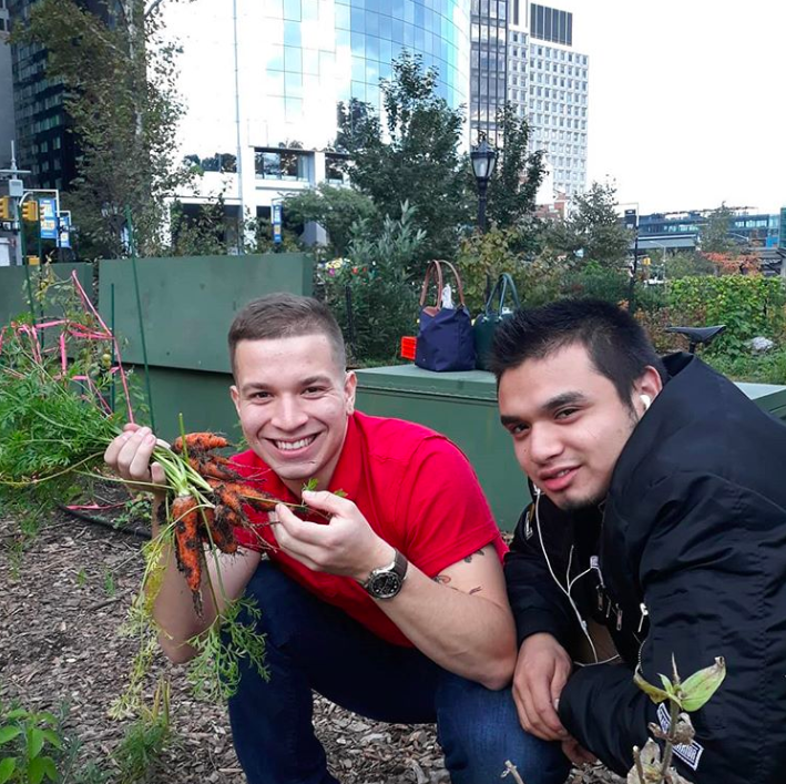  Group of City-As-School students posing outdoors with vegetables in school garden. 