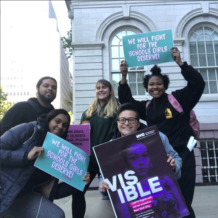  Group of City-As-School students posing outdoors with activist posters. 