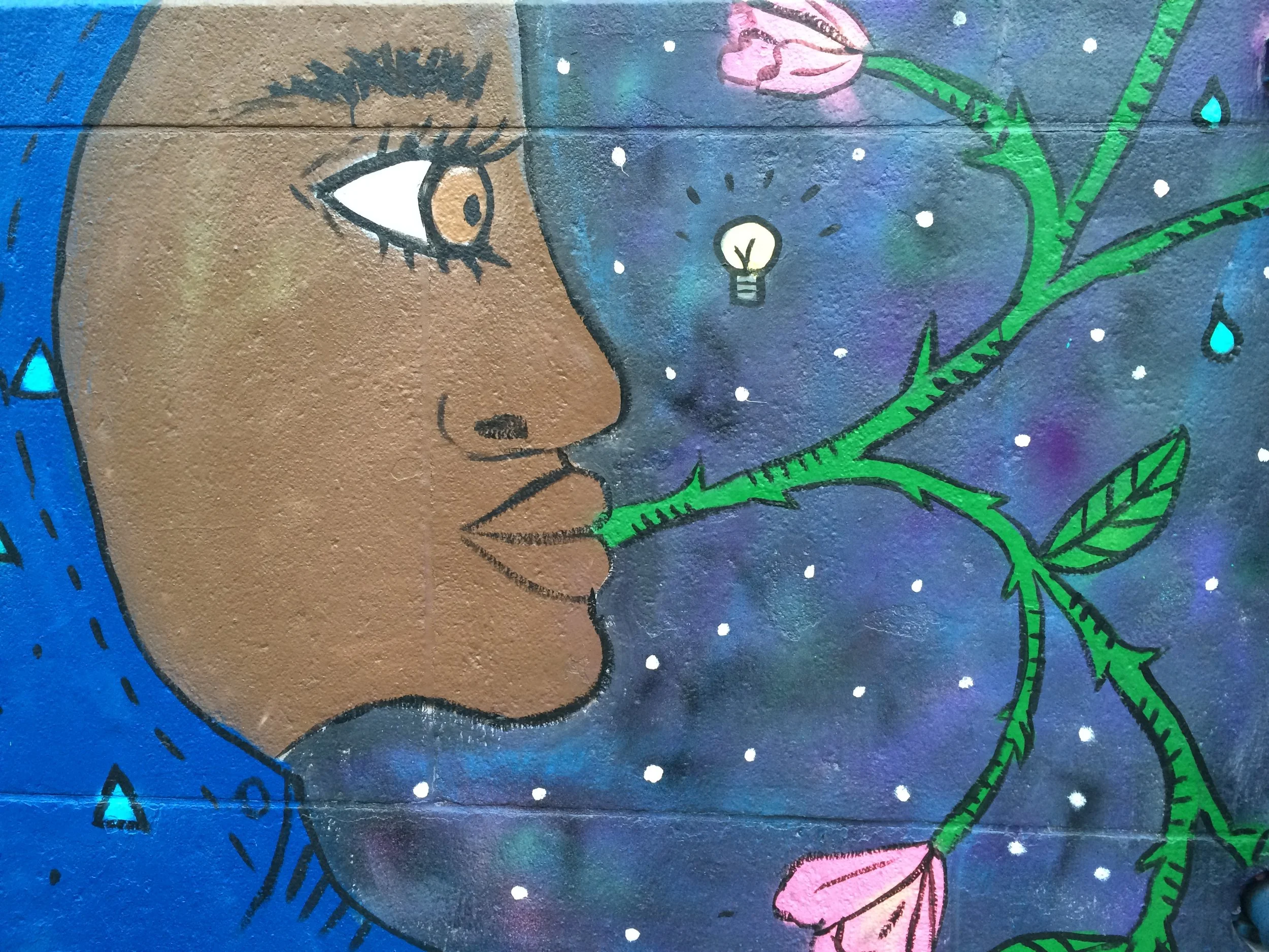  Colorful mural of young person of color and flowering vine against starry night sky on City-As-School exterior. 