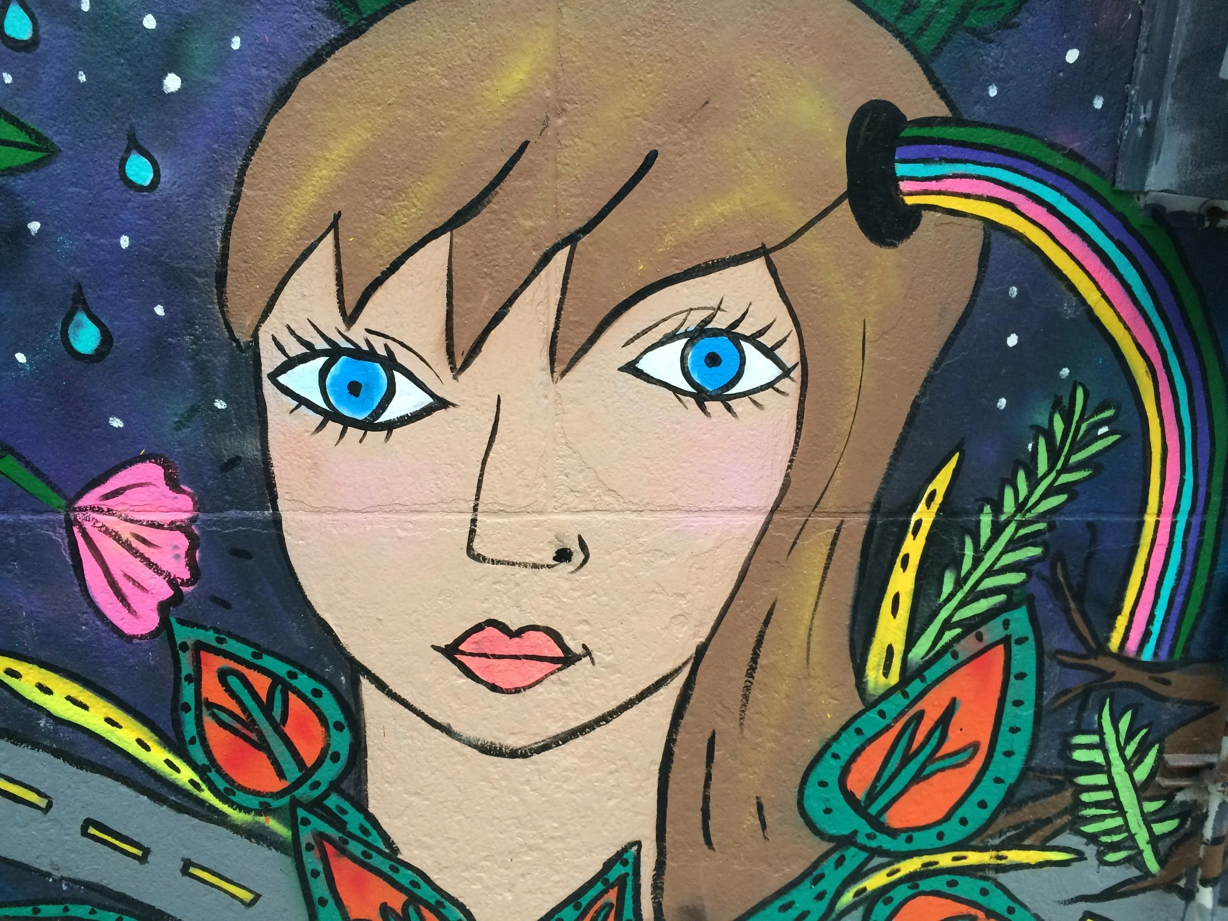  Colorful mural of young person, flowers and rainbow against night sky at City-As-School. 