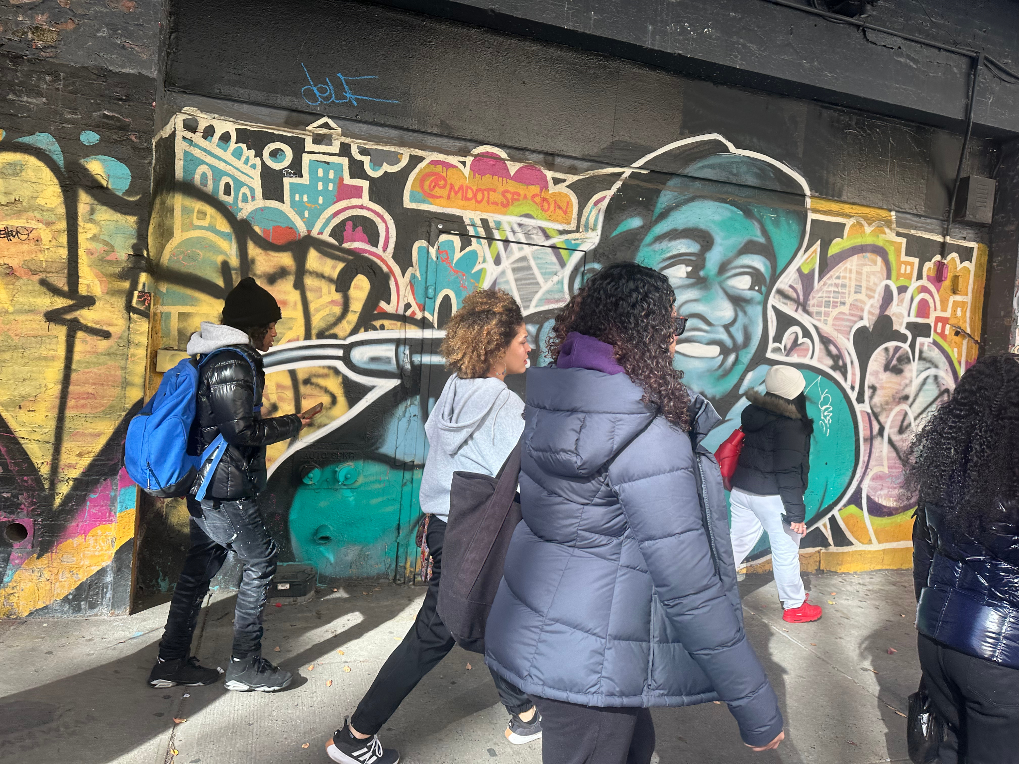 4 students and an adult crossing the street in Paris. Students in the foreground and the landscape of a Parisian street in the background.