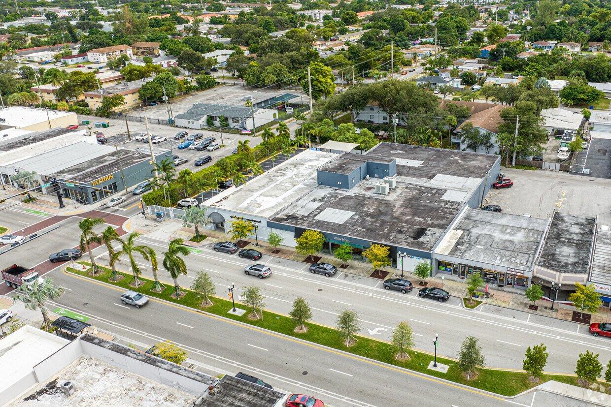 Aerial view of a commercial area with a salon, parking lots, and surrounding neighborhood with trees and houses.