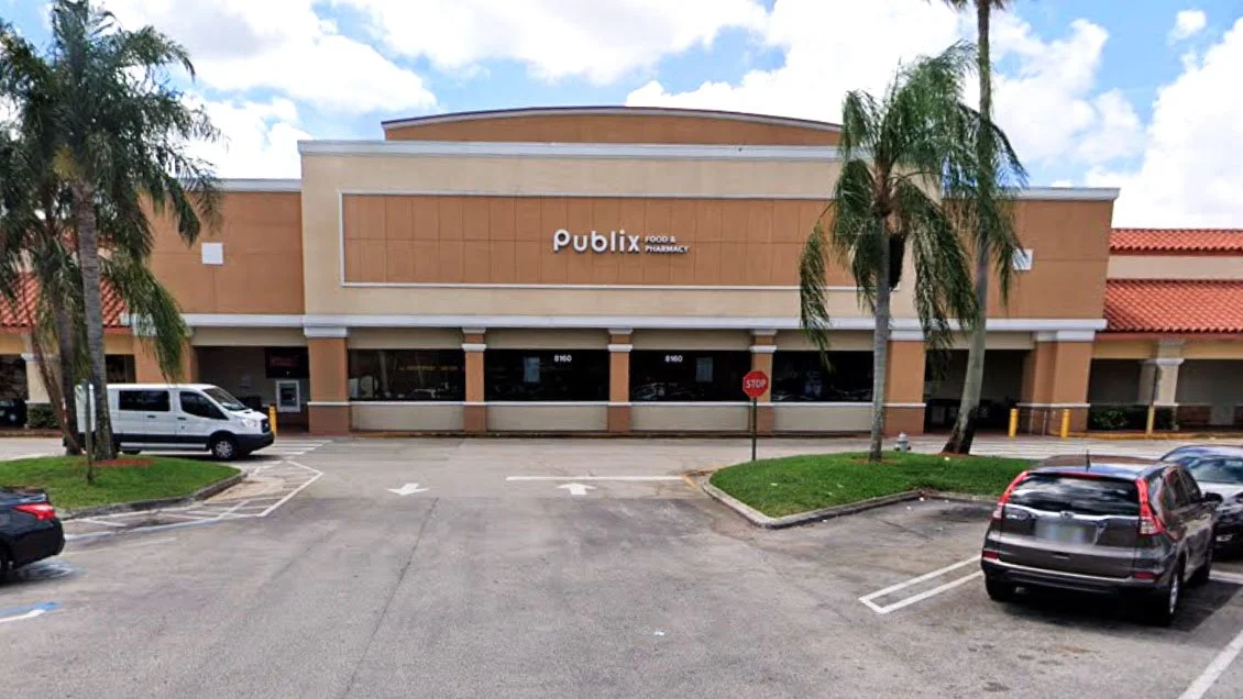 Front view of a Publix supermarket with parking lot and palm trees in Florida.