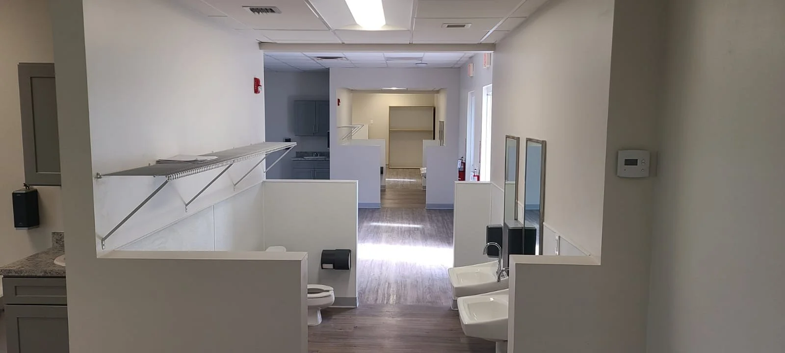 Empty nursing or medical facility with private booths, sinks, and restrooms.