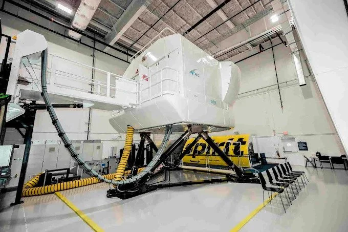 A view of the flight simulator from a different angle, highlighting its intricate machinery and the surrounding industrial environment.