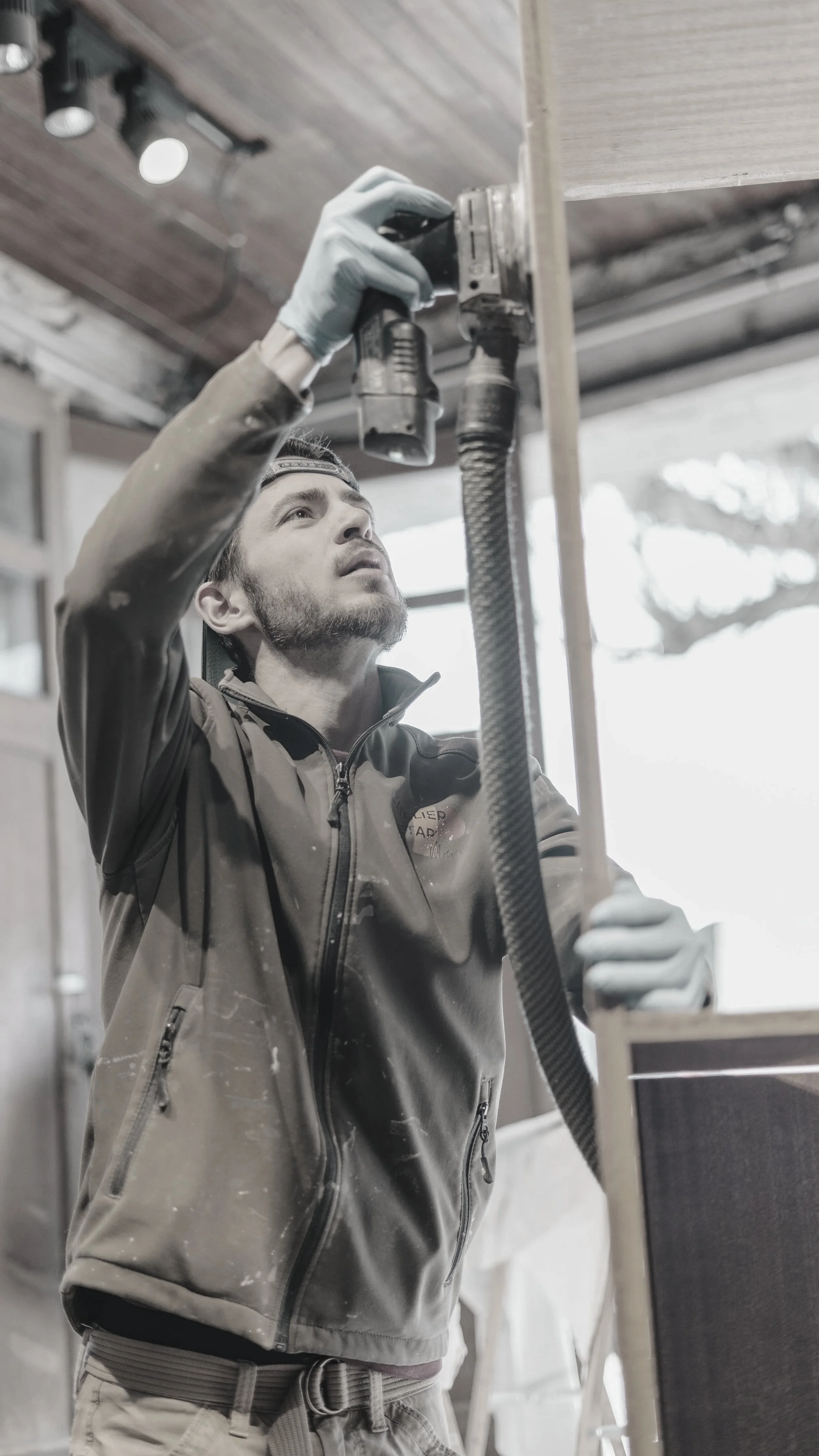 Un homme travaille avec une perceuse électrique dans un atelier en bois.