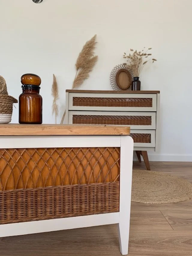 Une décoration intérieure avec un meuble en bois et rotin, des vases et des plantes séchées.