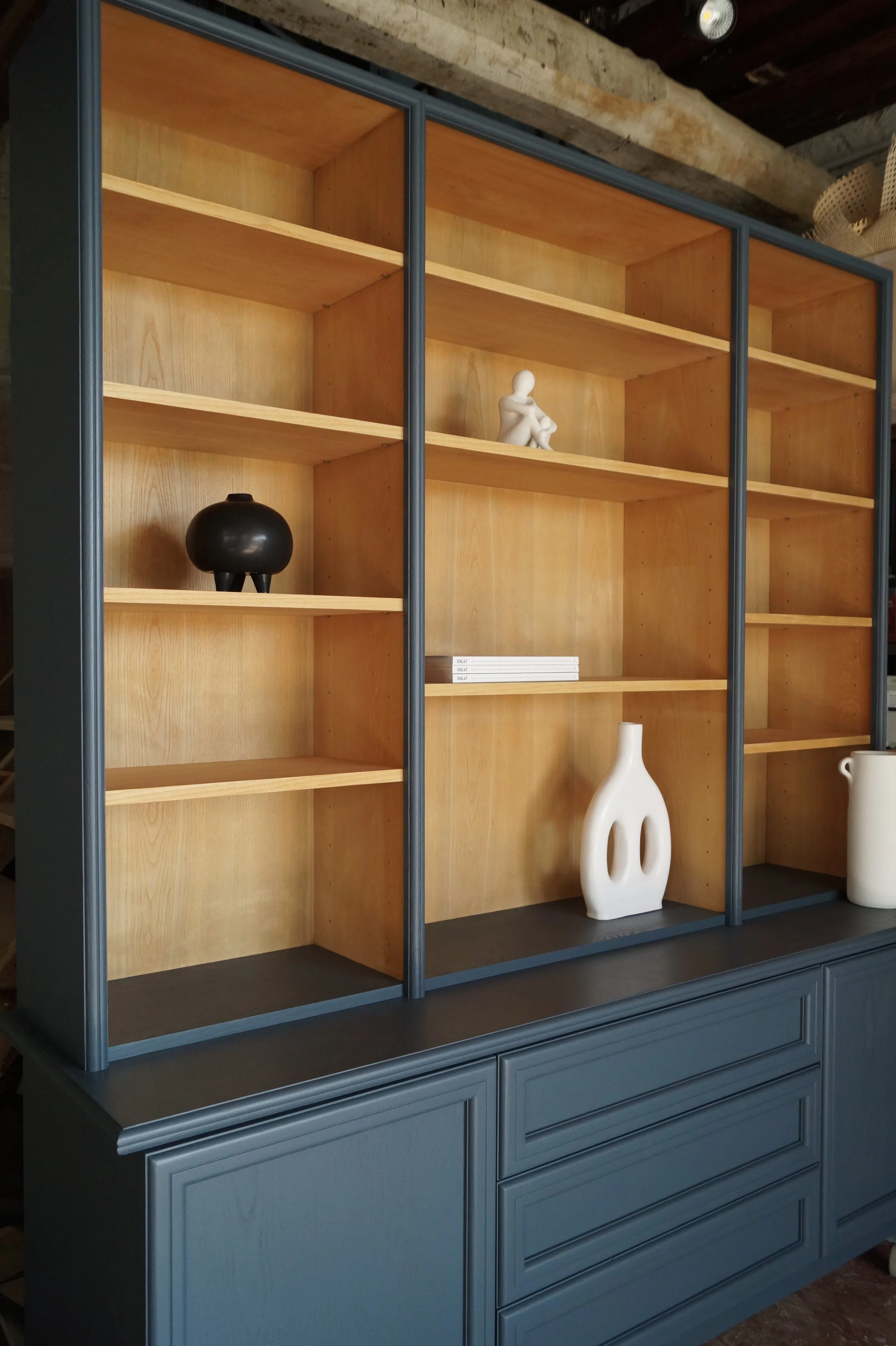Une grande étagère en bois rénové dans un bleu orage, contenant quelques vases et figurines décoratives