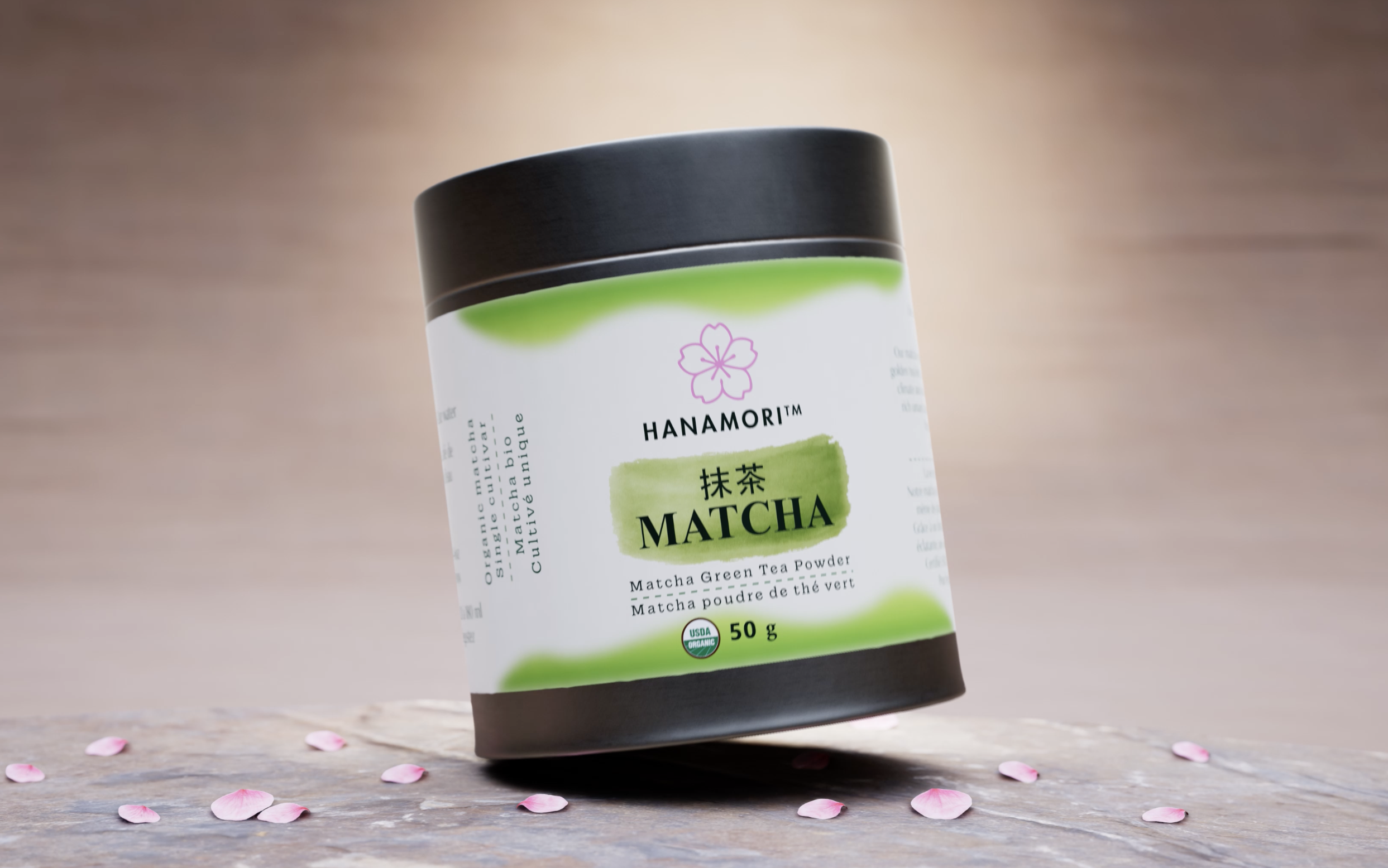 Hanamori organic matcha green tea powder container on a wooden table with pink flower petals