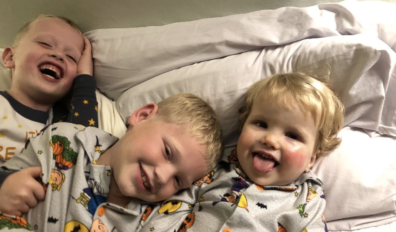 A photo of Annie Harpers's three children smiling and laughing while they lie beside each other on pillows