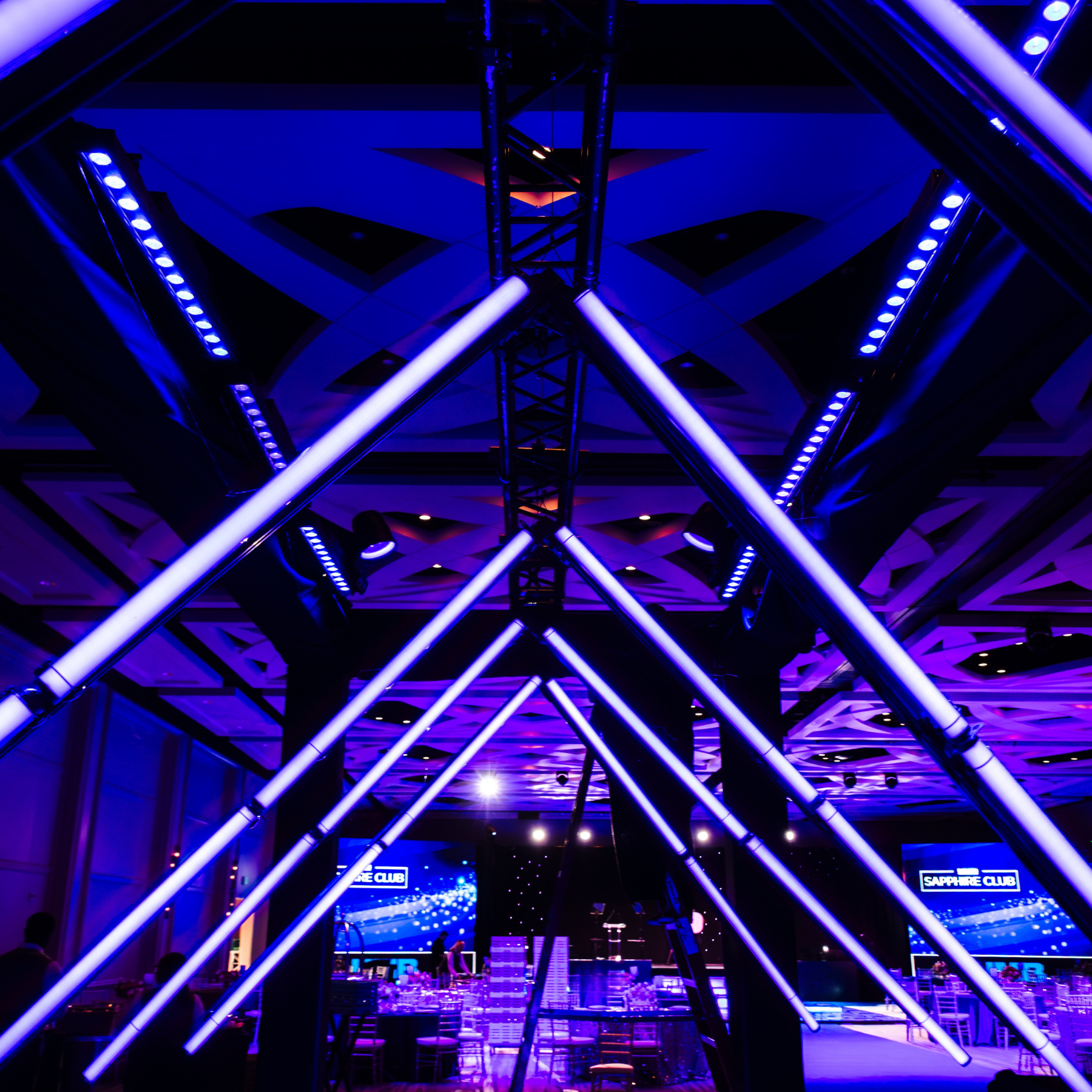 Modern house with large glass window, wooden exterior, situated in a mountainous landscape with dry grass and small trees.