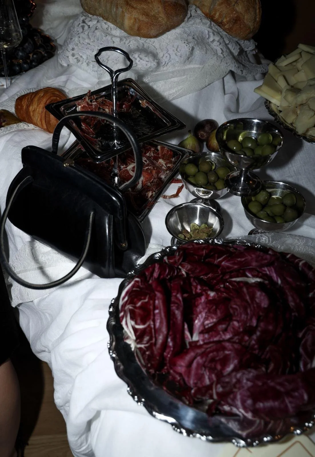 A table with a variety of food including bread, cheese, olives, cured meats, and a bowl of radicchio salad in SoHo.