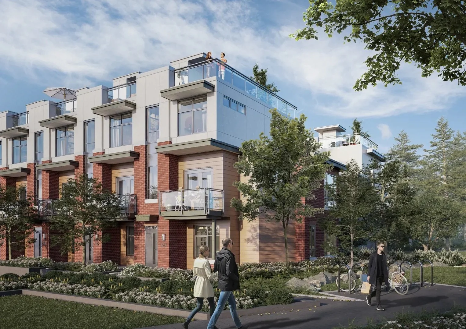 A modern multi-story residential building with brick and light-colored exterior walls, glass balconies, and rooftop terraces with people. There are trees, bushes, and flowers in the landscaped front yard. Pedestrians walk on the sidewalk, and a person walks by bike racks.