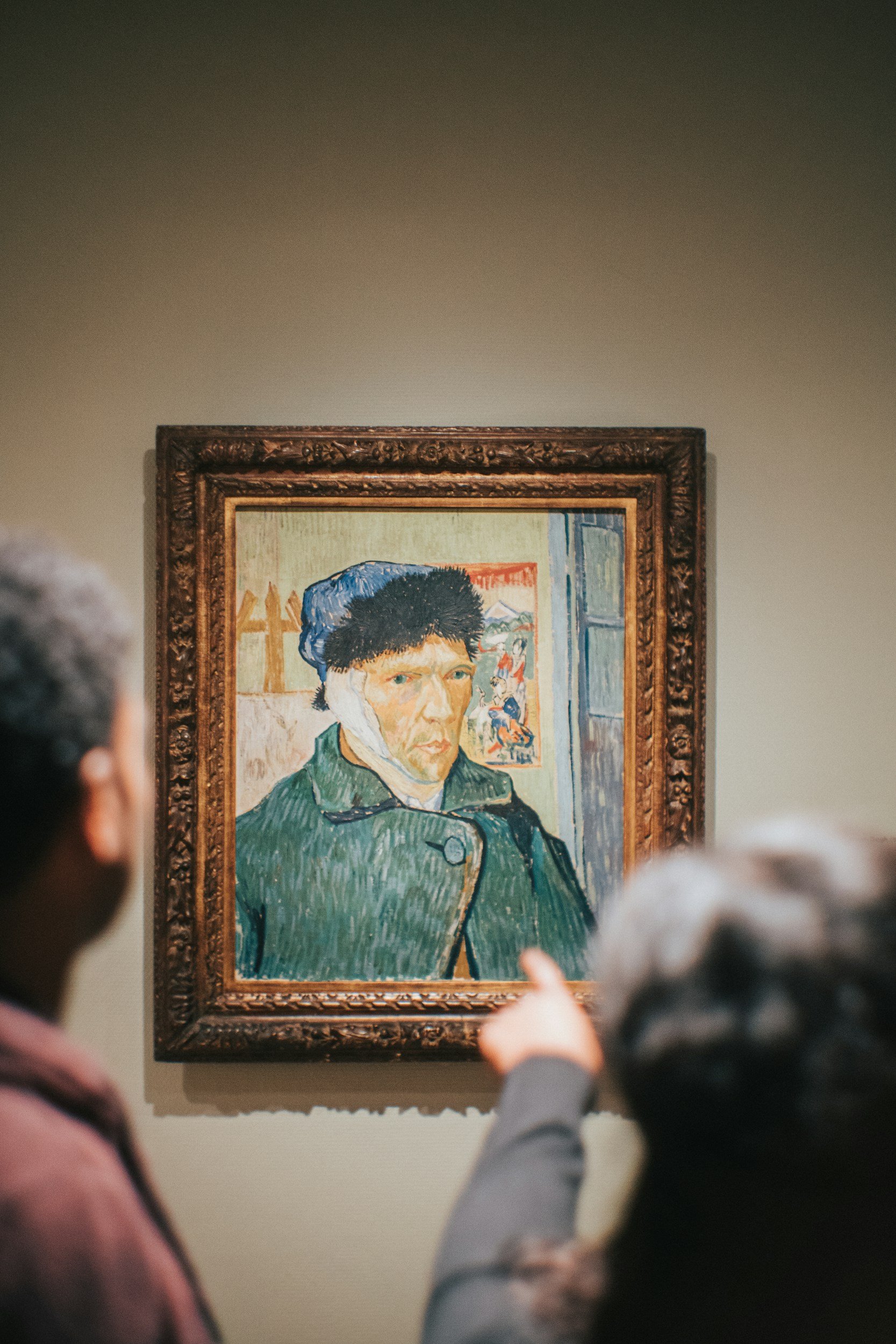 People viewing Vincent van Gogh's self-portrait painting in a museum.