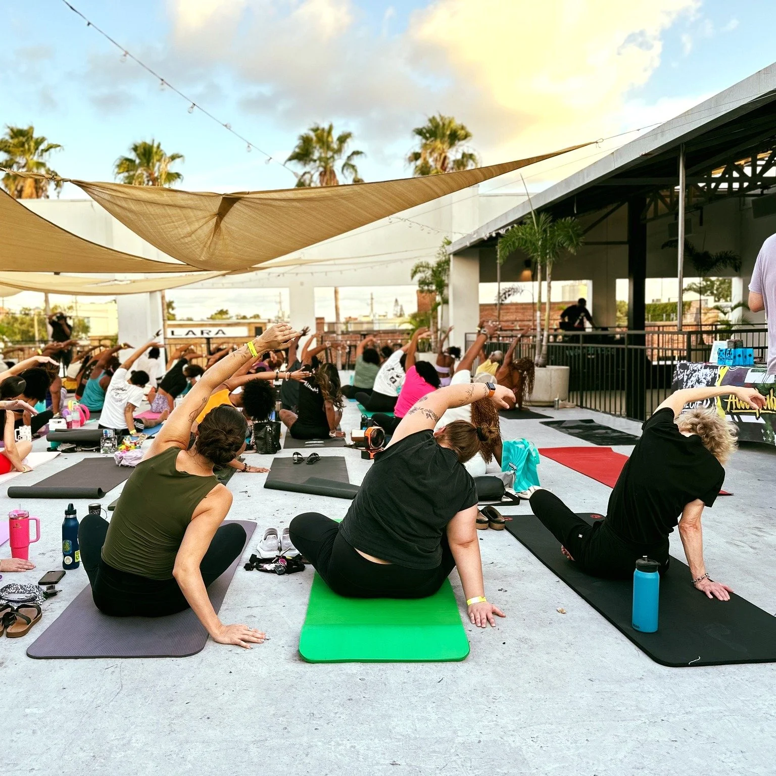 Outdoor rooftop yoga event in Tampa, FL featuring a diverse group of participants stretching at sunset. Hosted to promote holistic wellness and community engagement, this event reflects the mind-body approach of Dr. Julia Springs’ medical practice. I