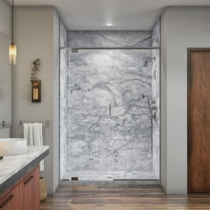 Modern bathroom shower area with marble walls and glass door.