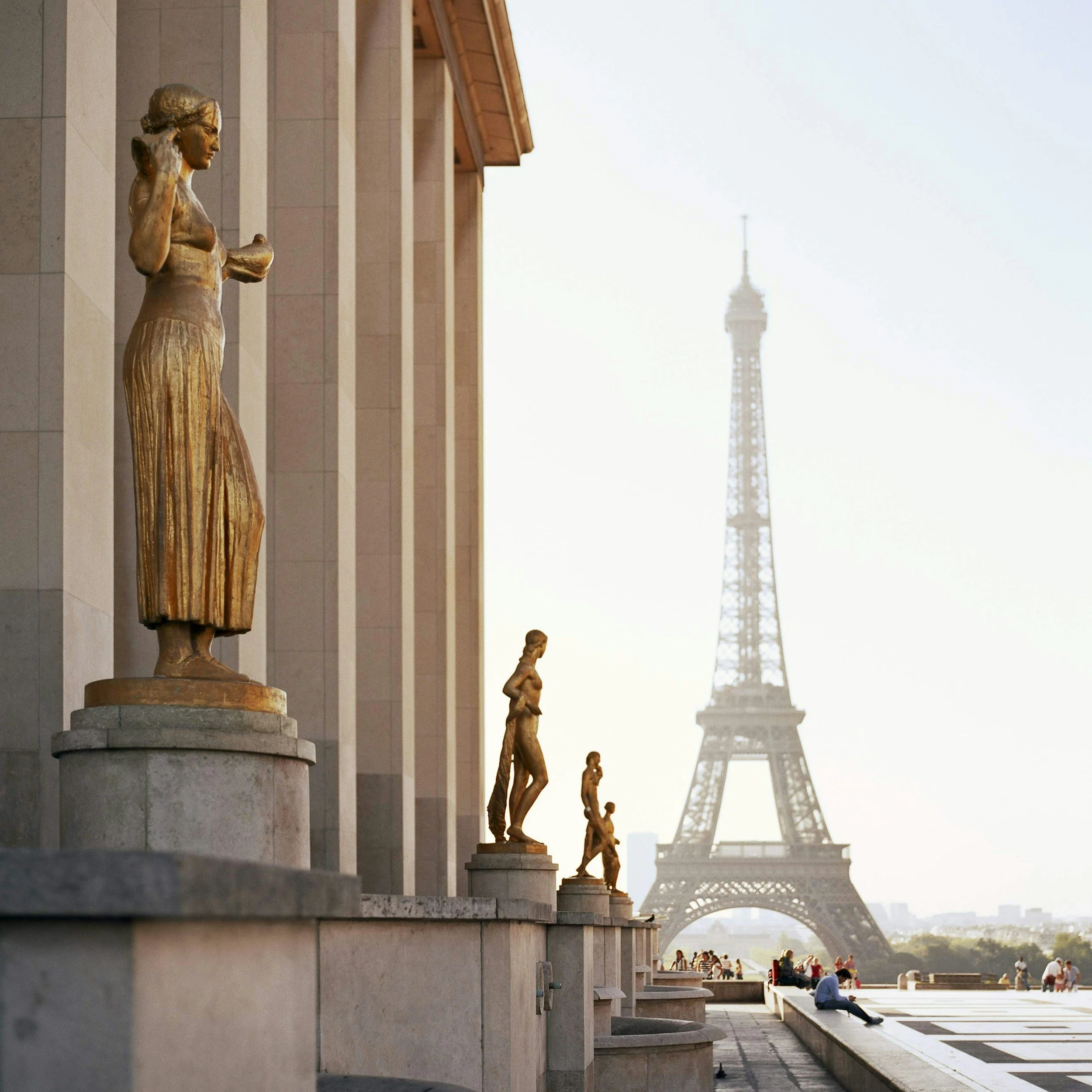 Statues of women along a terrace with the Eiffel Tower in the background in Paris, France.