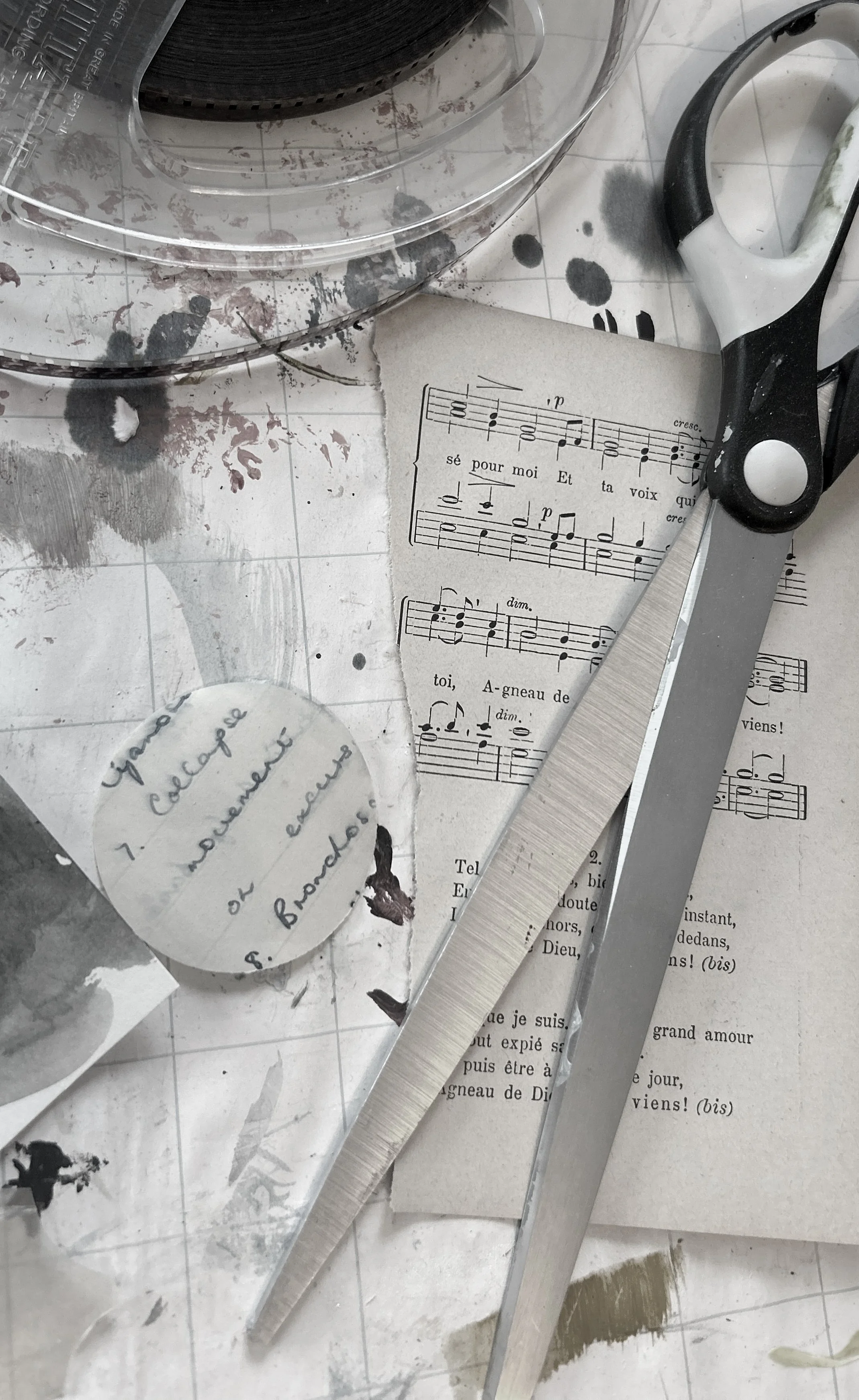Desaturated image of scissors, paint brushes, collage remnants including sheet music and paint marks