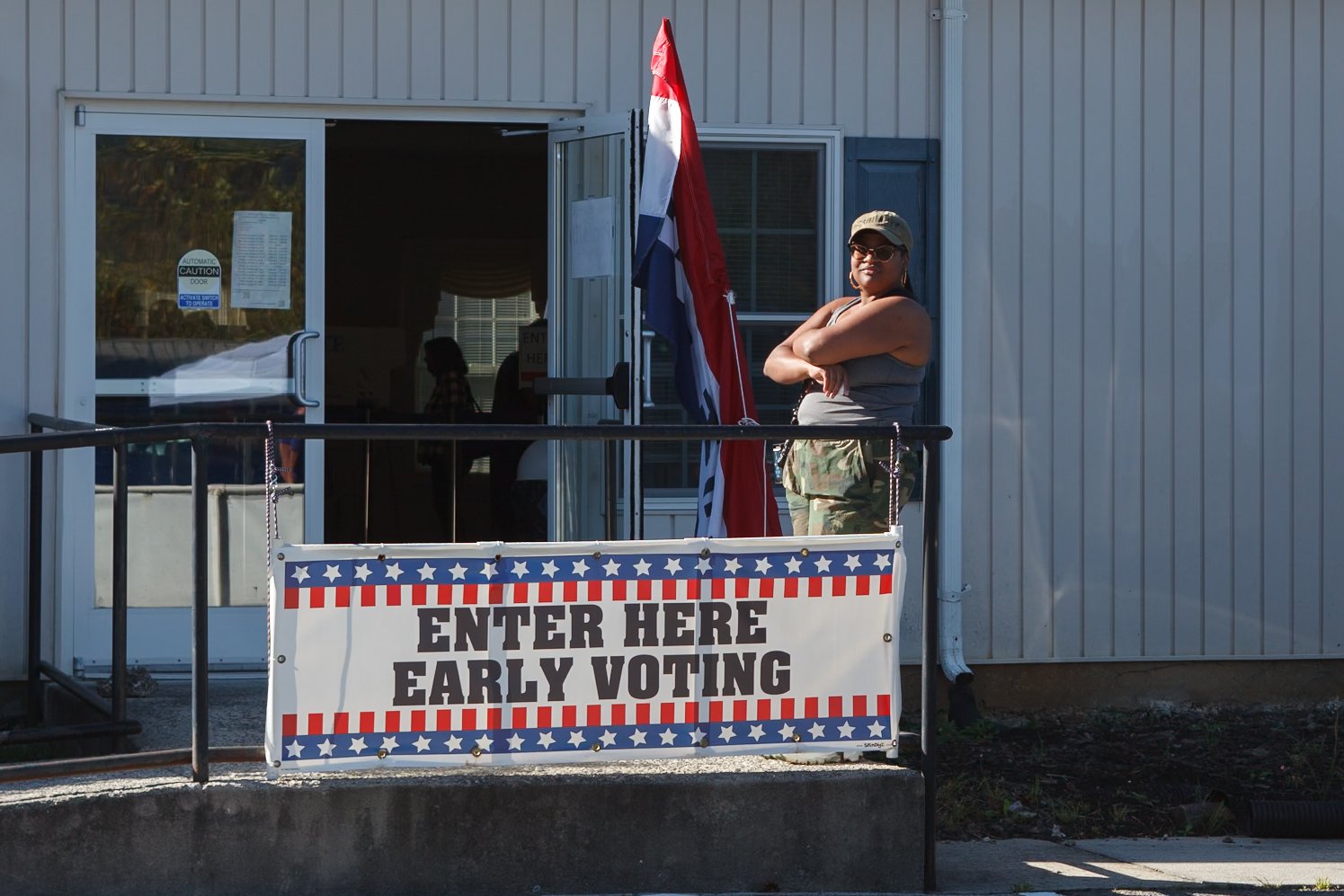    Waynesville, NC - October 15th, 2026.    Early voting Day 1. A woman stands at the entrance, observing.  