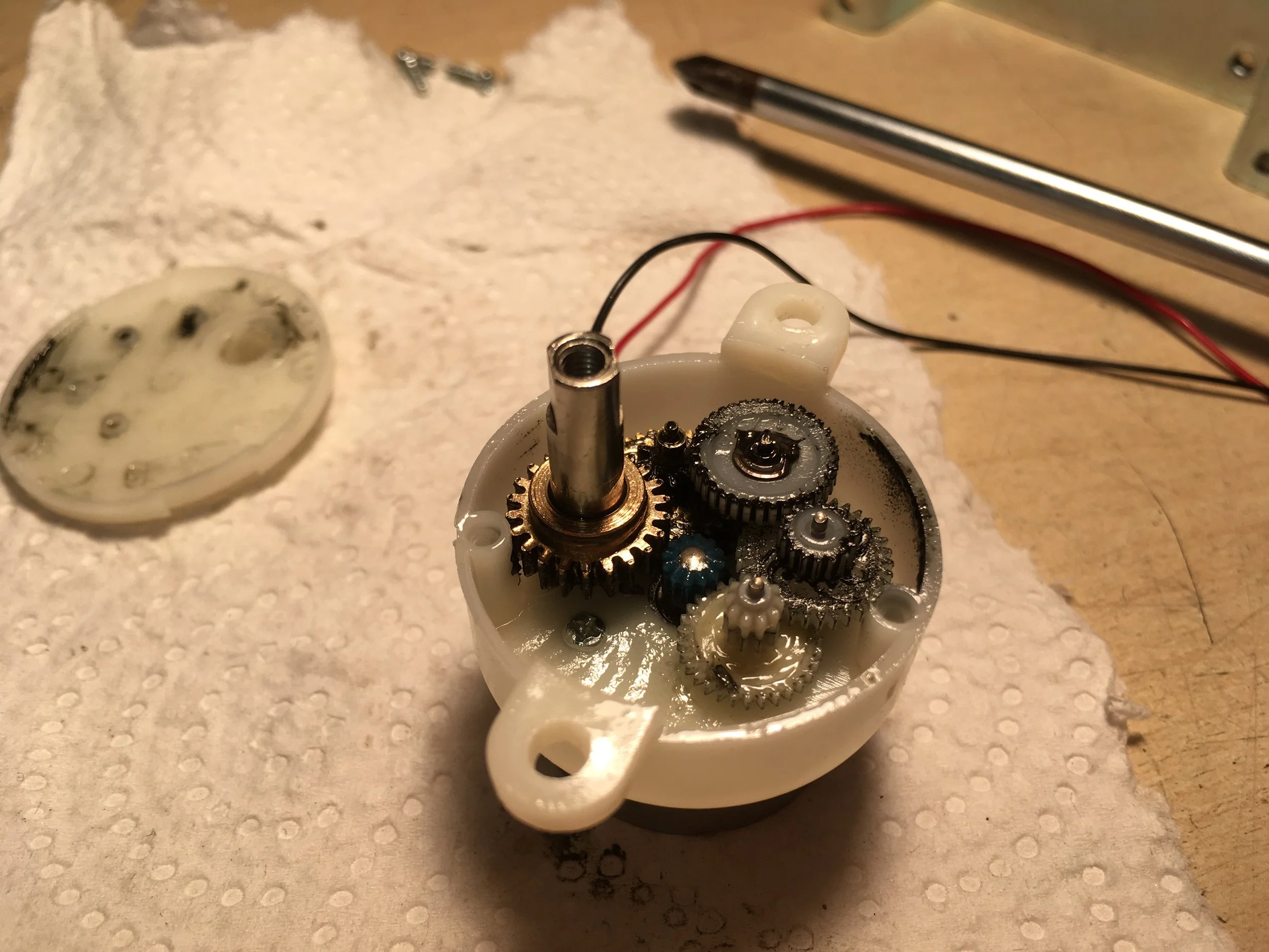 Getriebemotor aus einem Videoprojektor. Zu sehen sind die Antriebswelle sowie diverse Zahnräder.