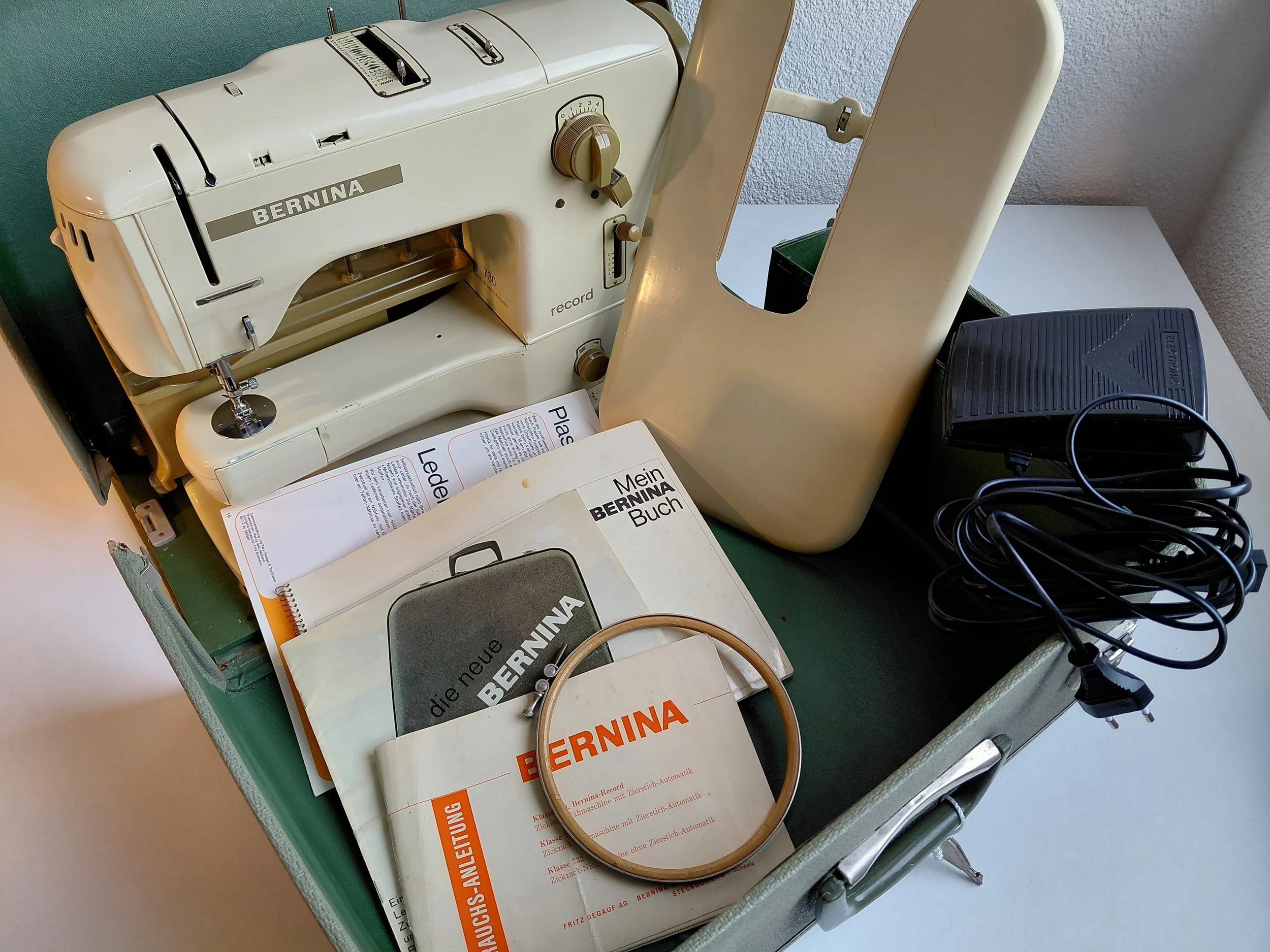 Revidierte Bernina 730 record Nähmaschine mit diversem Zubehör wie Nähfüssen, Fadenspulen und Fusspedal.