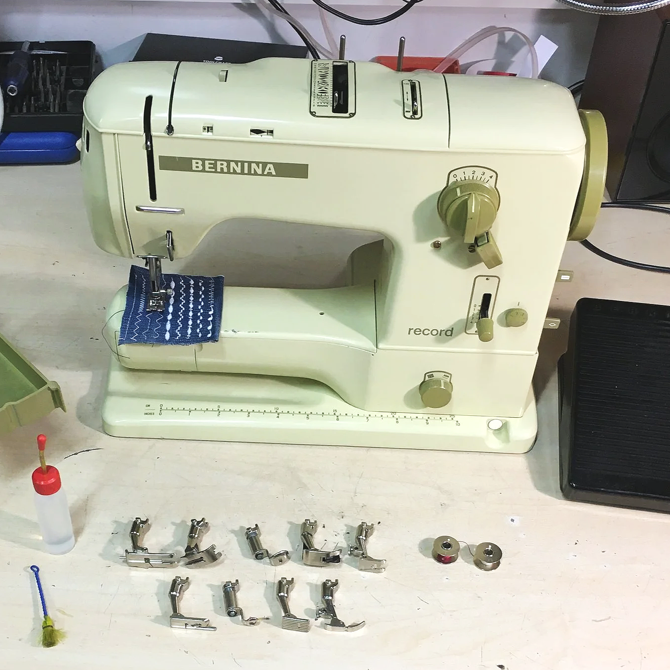Revidierte Bernina 530 record Nähmaschine mit diversem Zubehör wie Nähfüssen, Fadenspulen und Fusspedal.