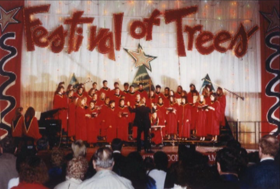 A choir in red robes performing on Center Stage at the Festival of Trees