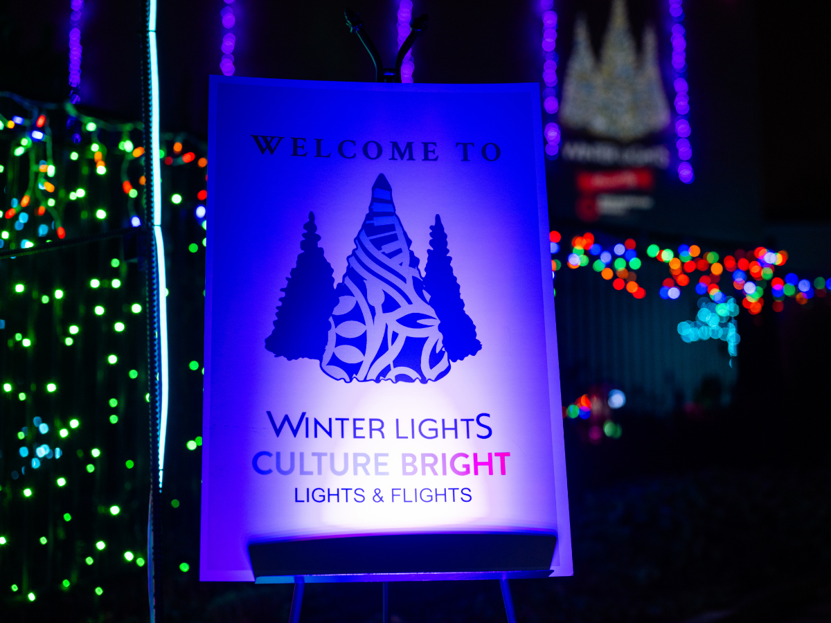 A sign promoting winter lights and holiday culture with colorful lights in the background.