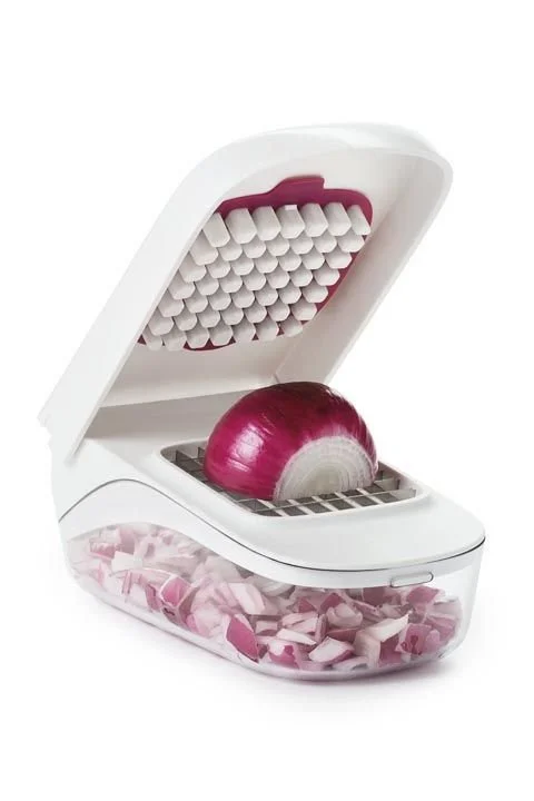 An automatic food chopper with a red onion inside and chopped onion pieces stored in a transparent compartment.
