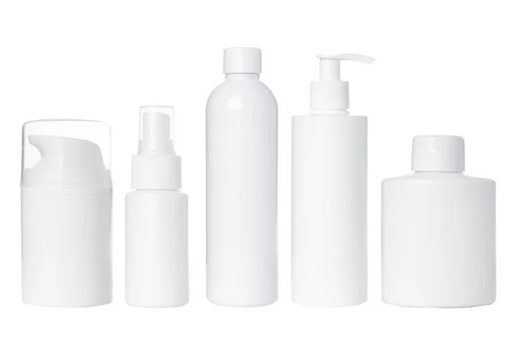 Five white cosmetic or skincare bottles with pump or spray dispensers, set against a white background.