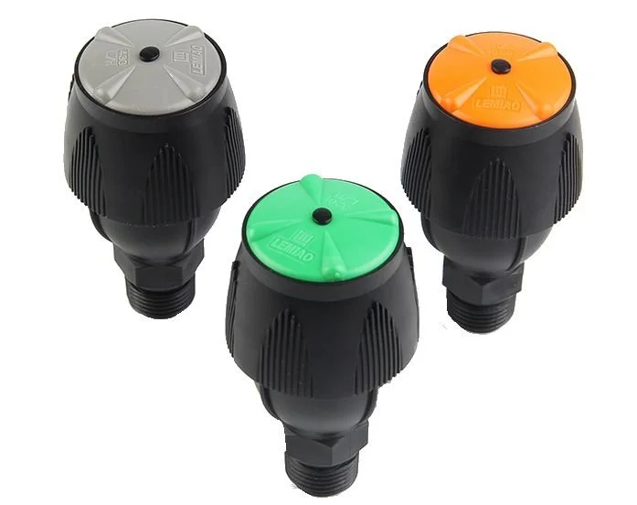 Three sprinkler heads with black bodies and different colored tops: gray, green, and orange, arranged in a triangle on a white background.