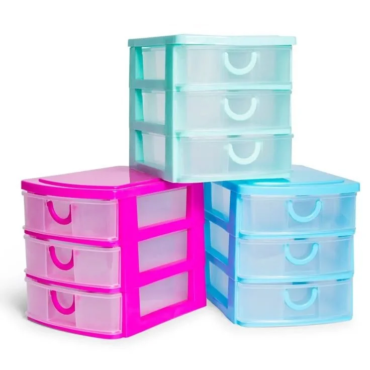Colorful plastic storage drawers in pink, blue, and green stacked on a white background.