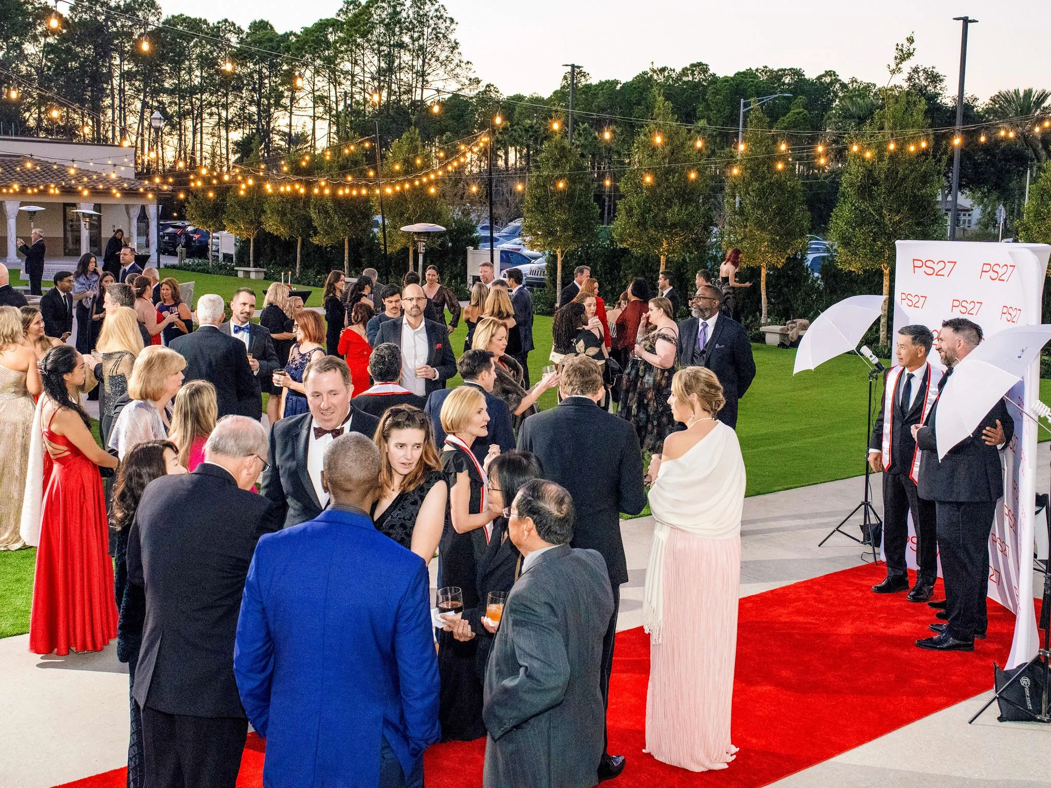 Guests gathering on the red carpet at an outdoor evening gala