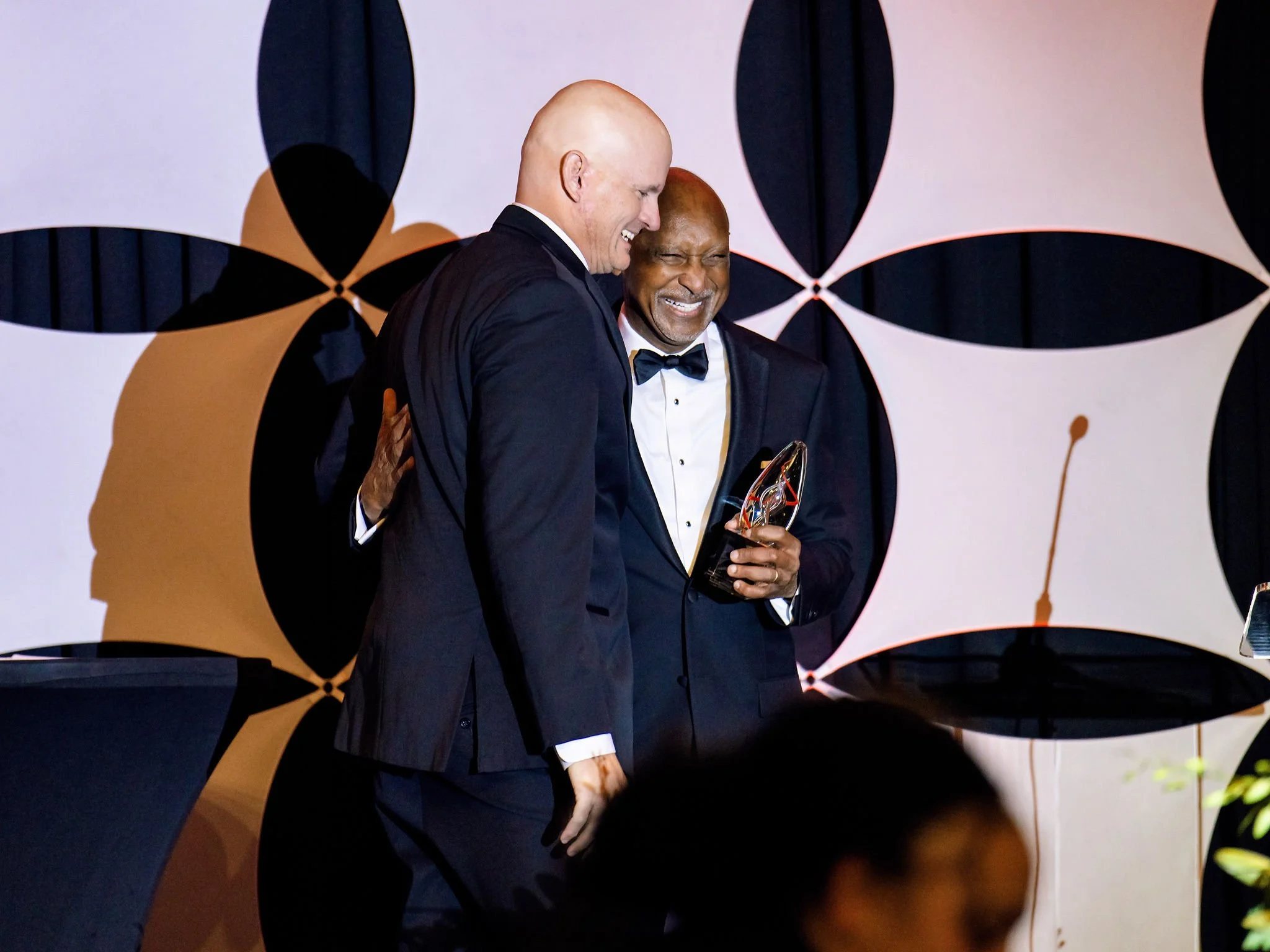 Two guests embracing at an awards ceremony