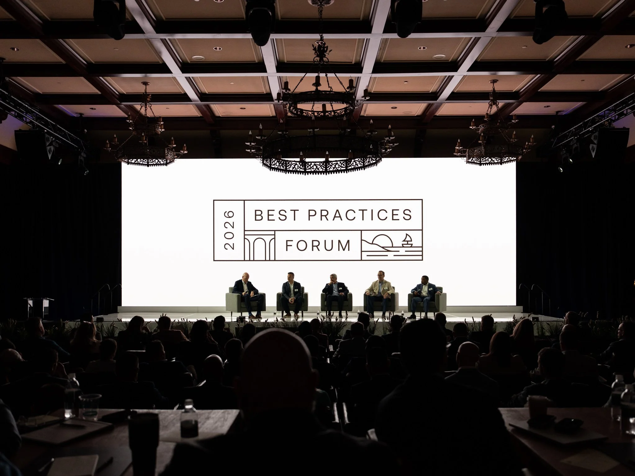 Panel speakers on stage in a dark conference ballroom