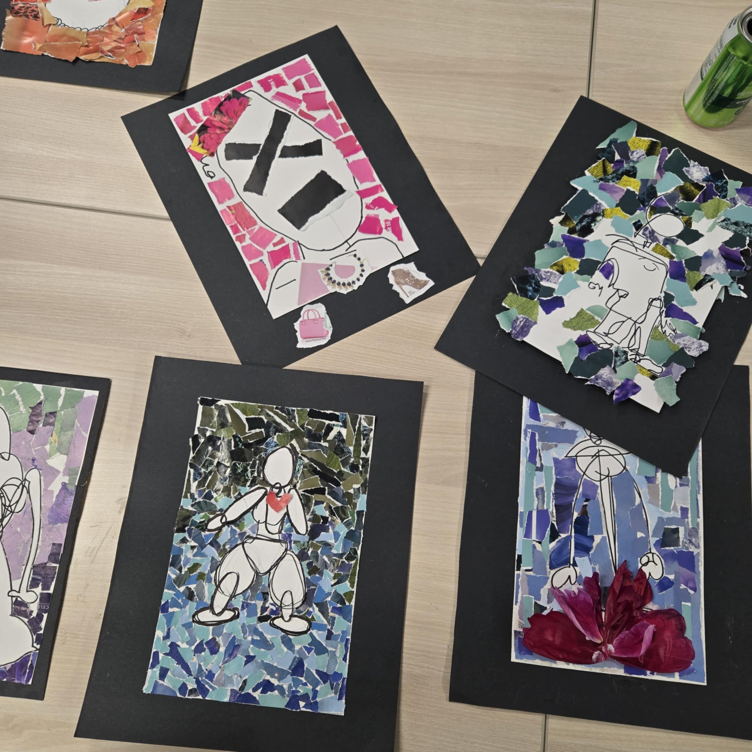 Four mixed media art collages on black paper, depicting abstract human figures with colorful torn paper backgrounds, arranged on a light wooden table.