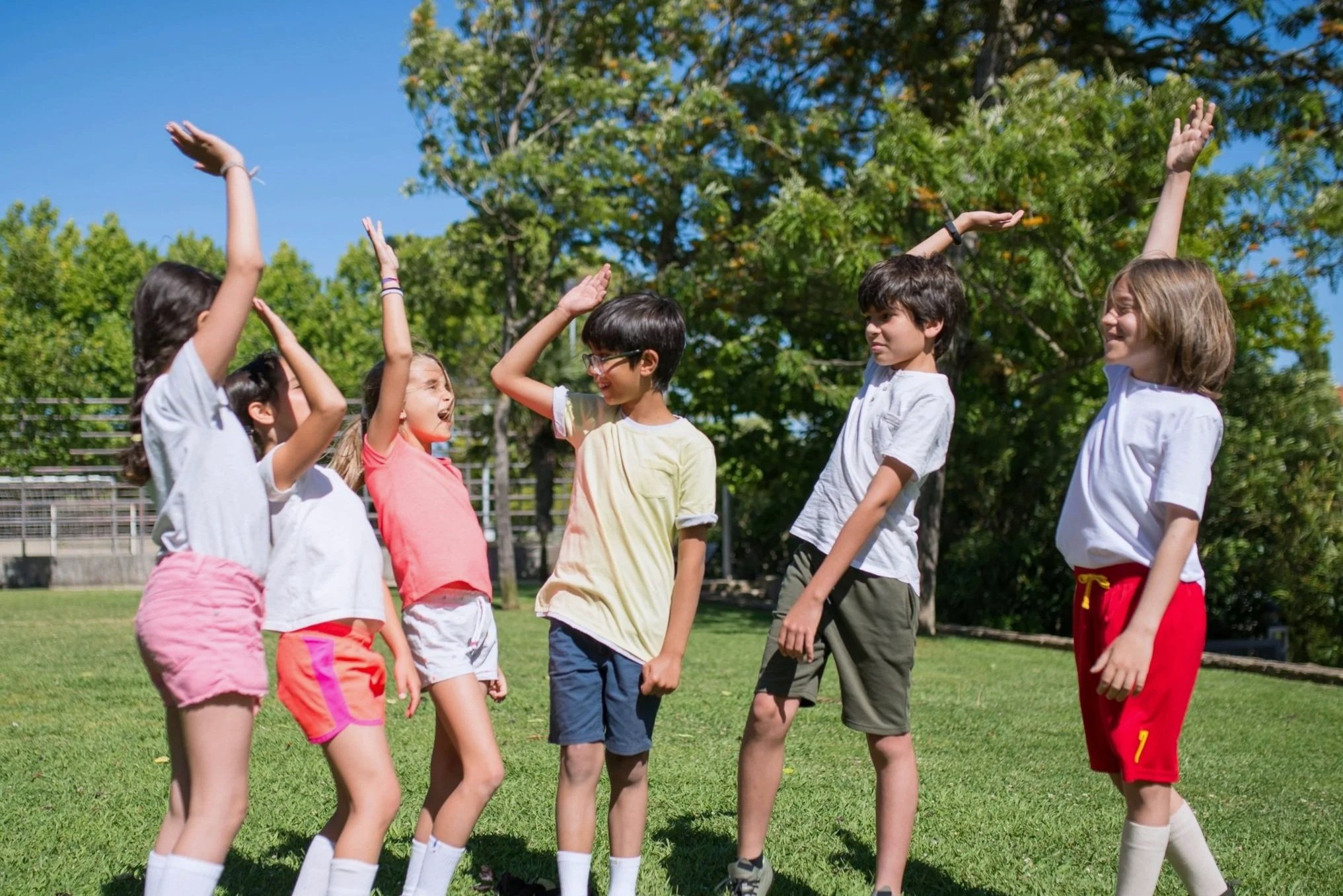 Group of children meditating or practicing mindfulness while sitting cross-legged on green carpet with eyes closed.