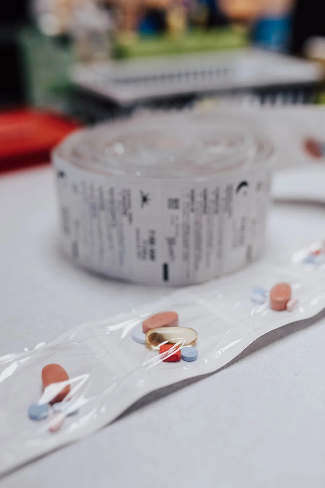 Blurry photo of a white medication bottle in the background and assorted pills on a blister strip in the foreground.