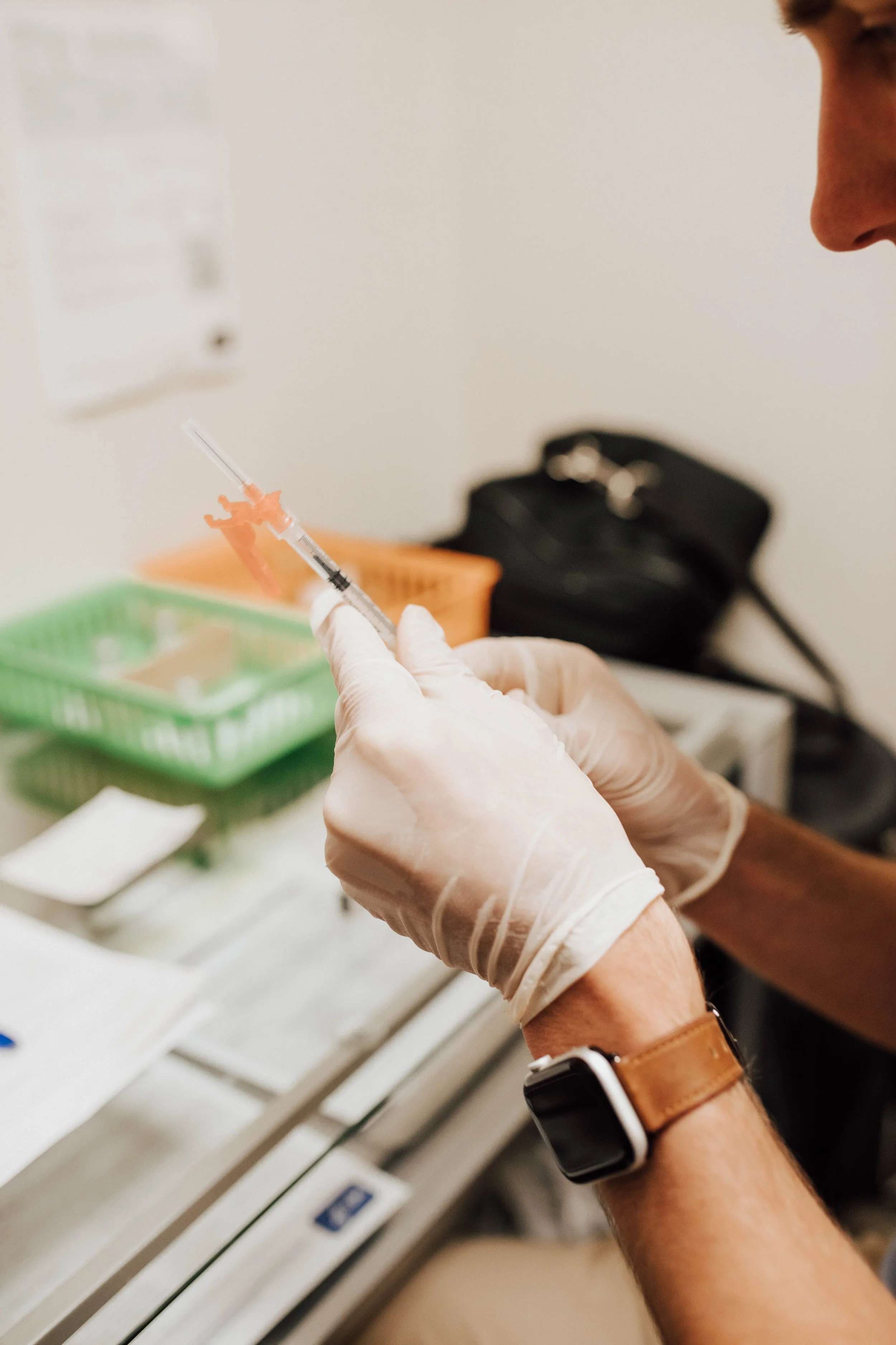 A person wearing gloves prepares a syringe with vaccine or medication in a clinical setting.