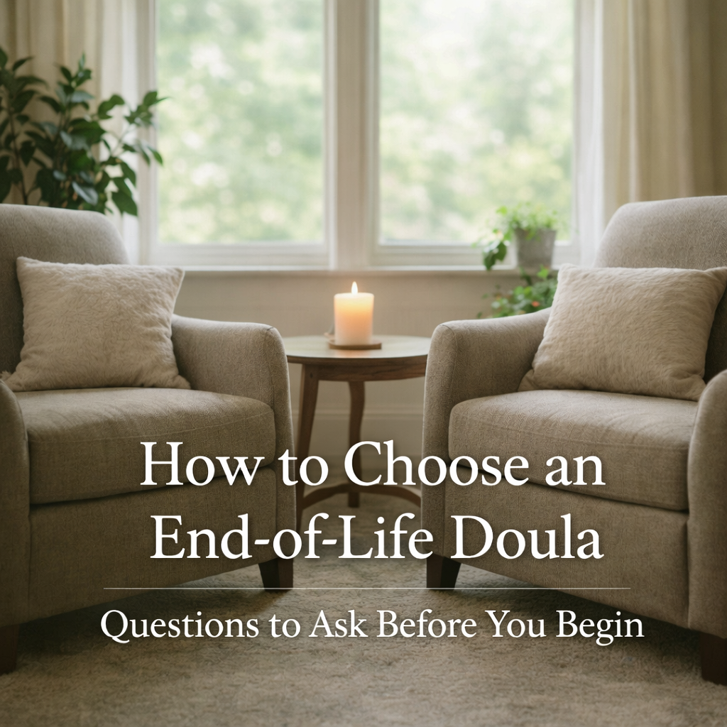 Two soft, plush chairs angled toward each other in a warmly lit living room, with a small table and glowing candle between them, natural light coming through a window with greenery visible outside.