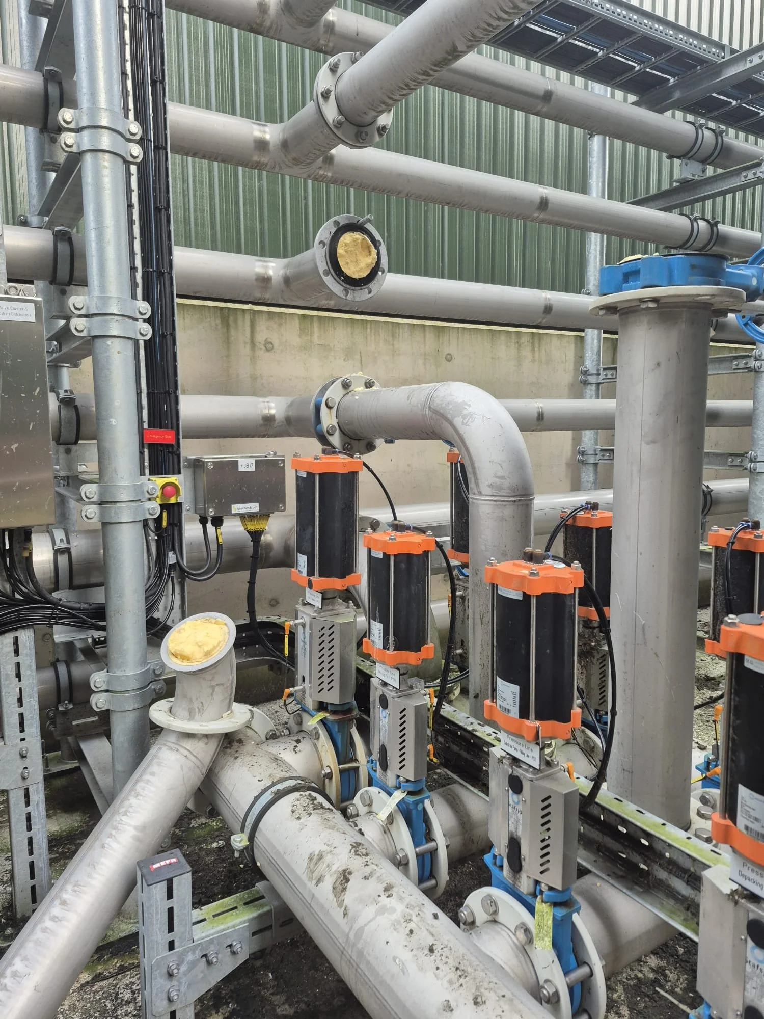 Industrial piping system with valves, sensors, and electrical connections in a mechanical or water treatment facility.