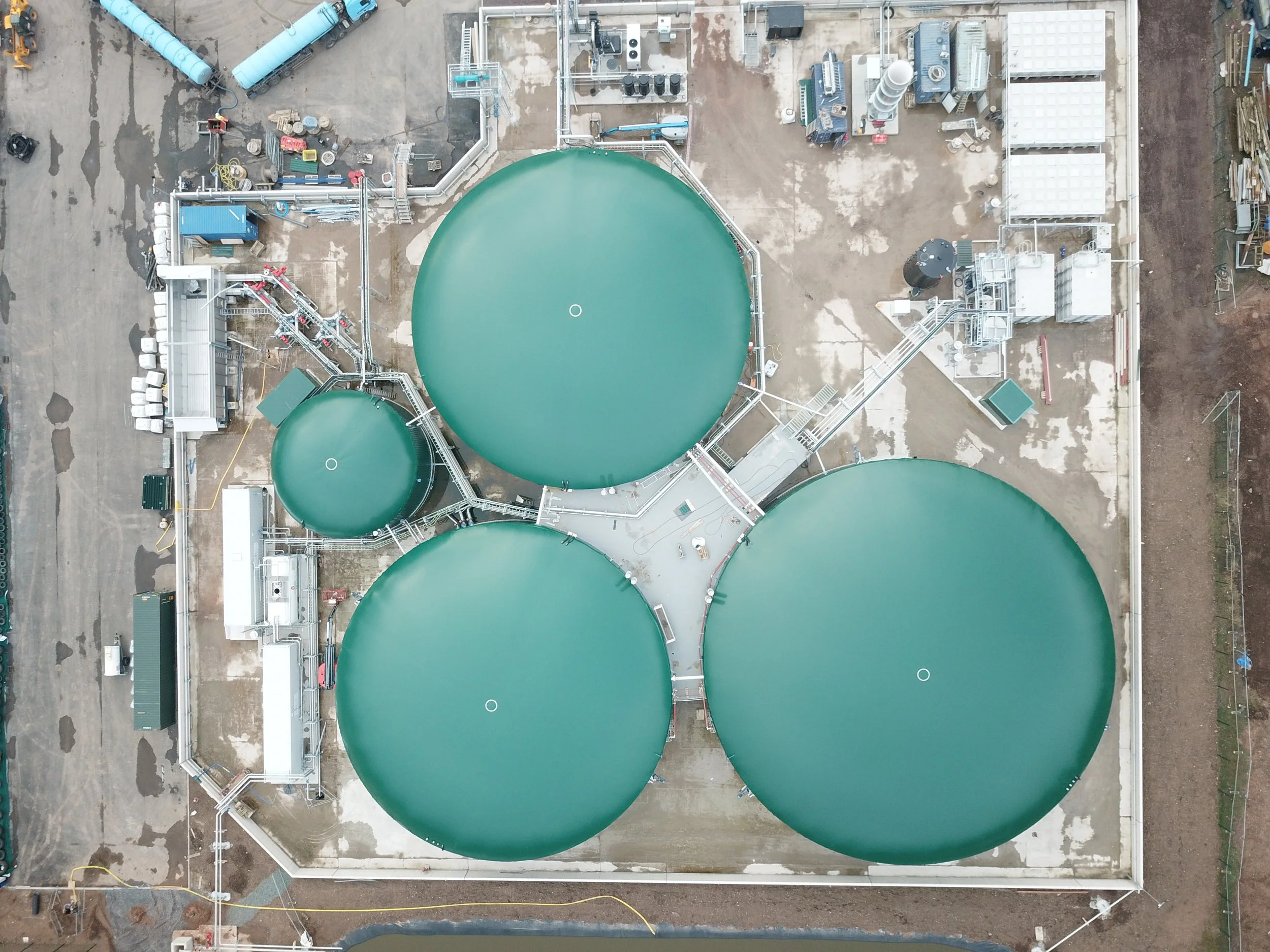 Aerial Drone view of 3 large green AD plant tanks, 1 small tank, live biogas plant