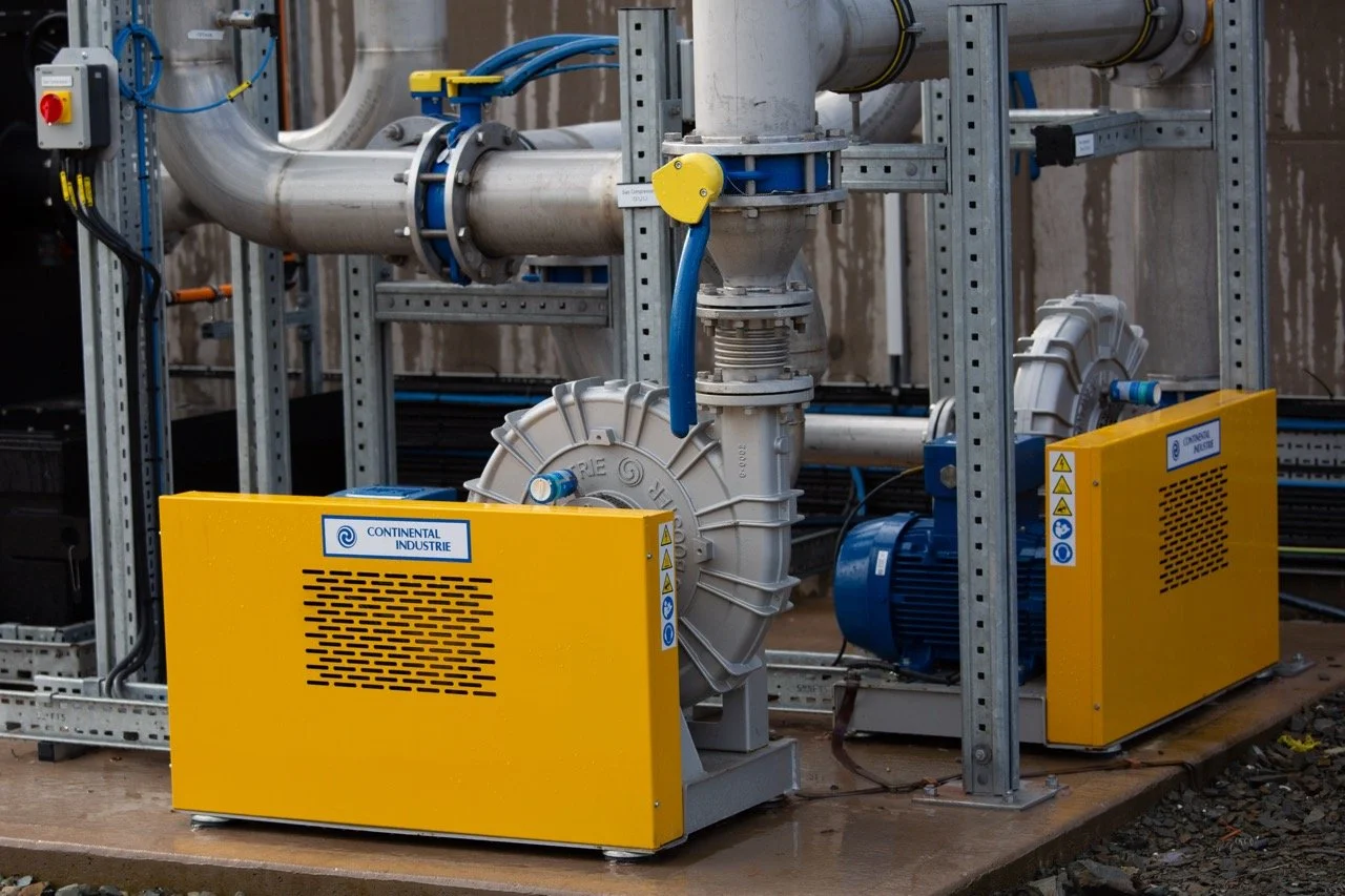 Industrial equipment with yellow and blue covers, pipes, and machinery in a factory setting.
