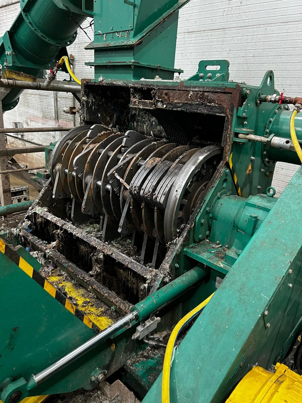 Damaged industrial machine with exposed and burnt internal components, including broken metal parts and debris.
